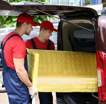 Günstig umziehen in Bad Homburg: Umzugshelfer laden ein gelbes Sofa in einen Transporter
