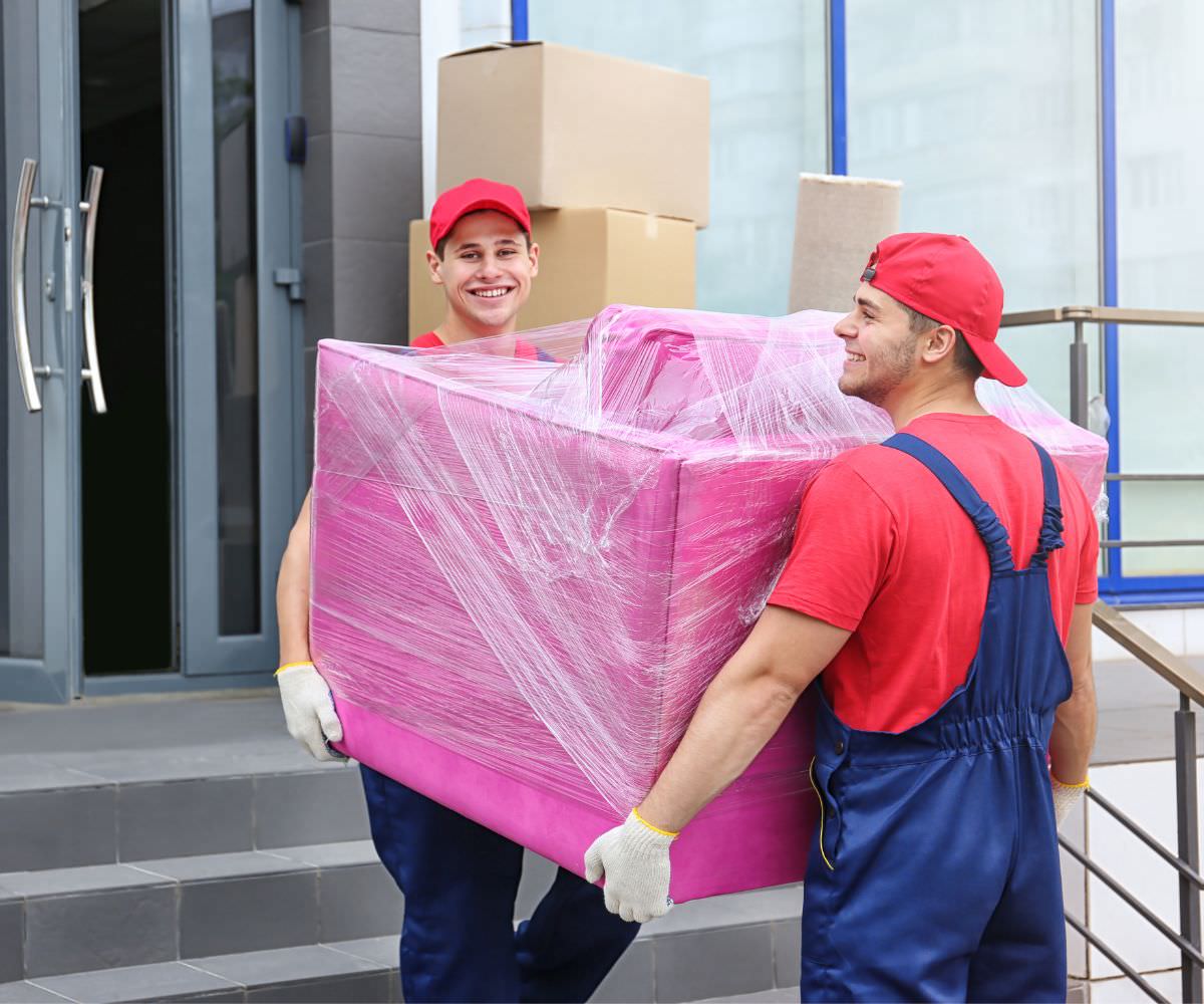 Umzugsservice: Zwei Umzugshelfer tragen ein in Folie gepacktes Möbelstück